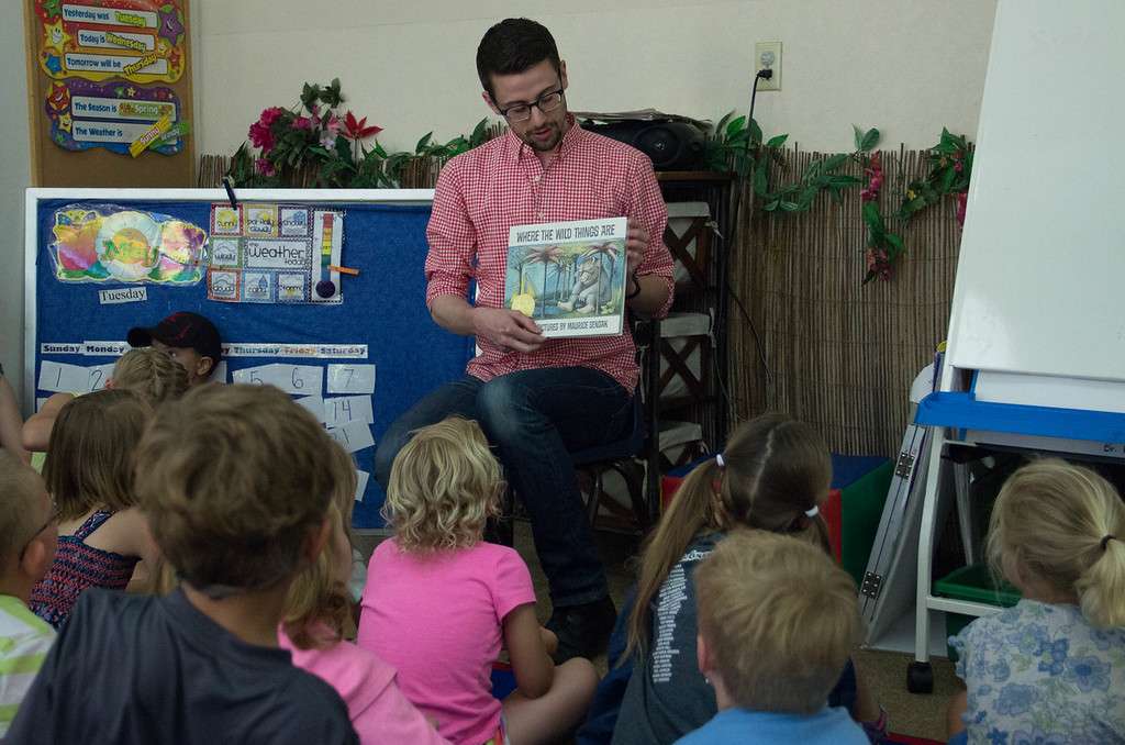 CSC graduate Travis Hencey reads "Where the Wild Things Are" to children at the Chadron State College Child Development Center Tuesday, May 31, 2016. He led an art workshop afterward encouraging the children to draw their best monsters. (Photo by Tena L. Cook/Chadron State College)