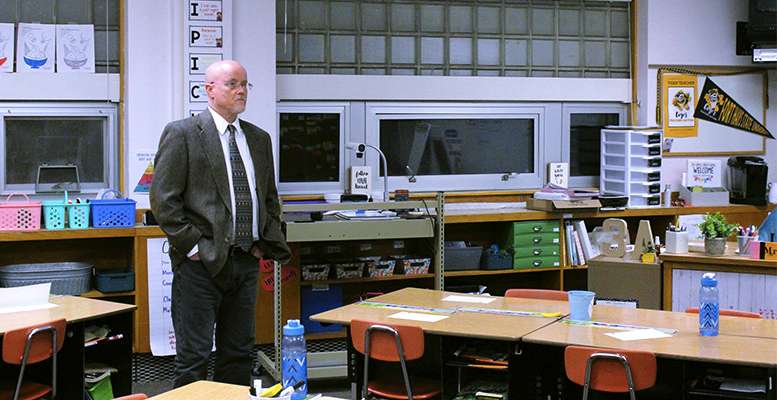 USD 489 Board President Mike Walker stands in front of a bank of windows in a Lincoln classroom. Water blows in through these windows when it storms.