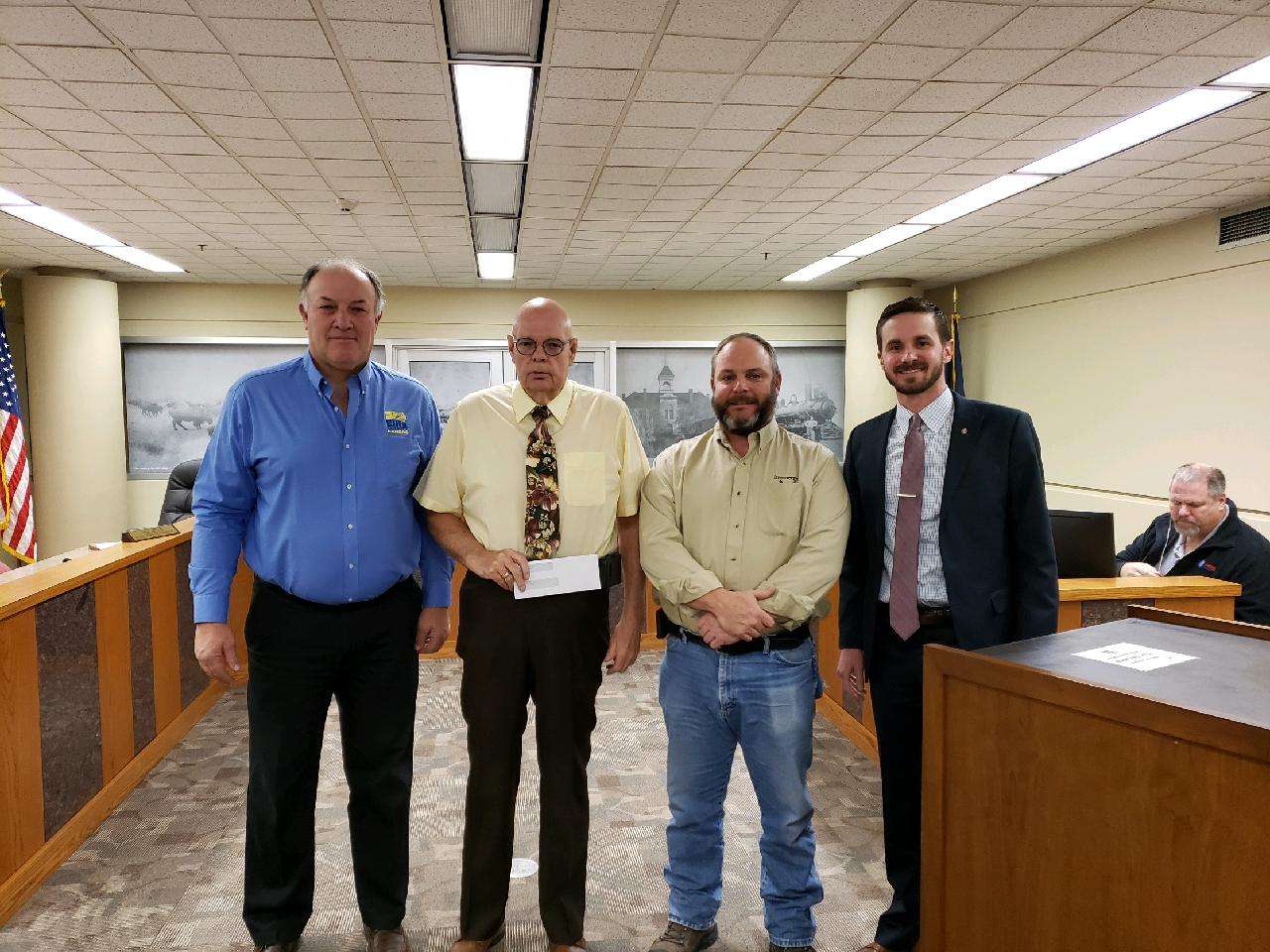 Invenergy's Shaun Braun presents the Ellis County Commission with a donation for emergency services Monday.