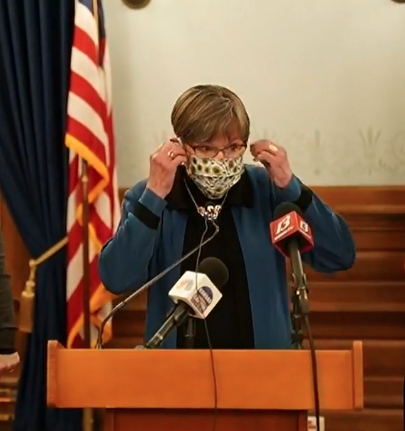 Gov. Laura Kelly puts on her mask during her Tuesday news conference