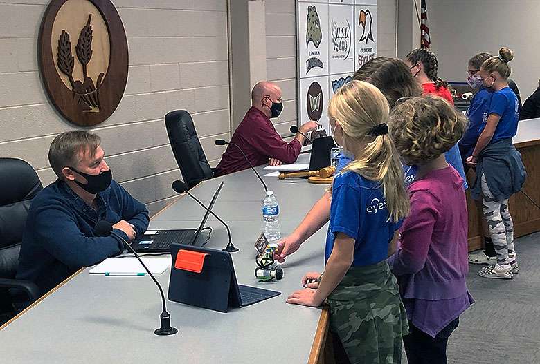 O'Loughlin fifth-graders Kesa Tsereteli, Evie Dietz and Emily Zolnierz demonstrate a Lego robot for school board member Allen Park at the Hays school board meeting Monday night.