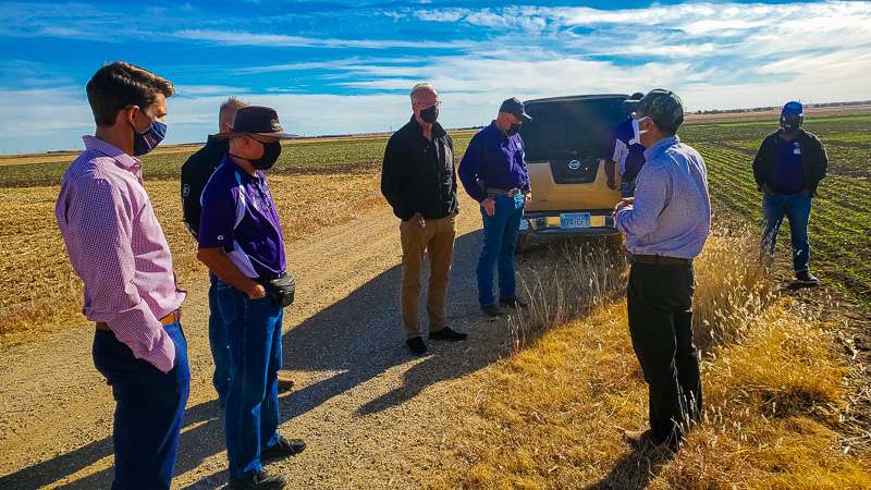 K-State Agreciculutre Research center wheat breeder&nbsp;Zhang Guorong speaks with U.S. Sen. Jerry Moran, R-Kan., with other scientists gathered around near a wheat field at the station.