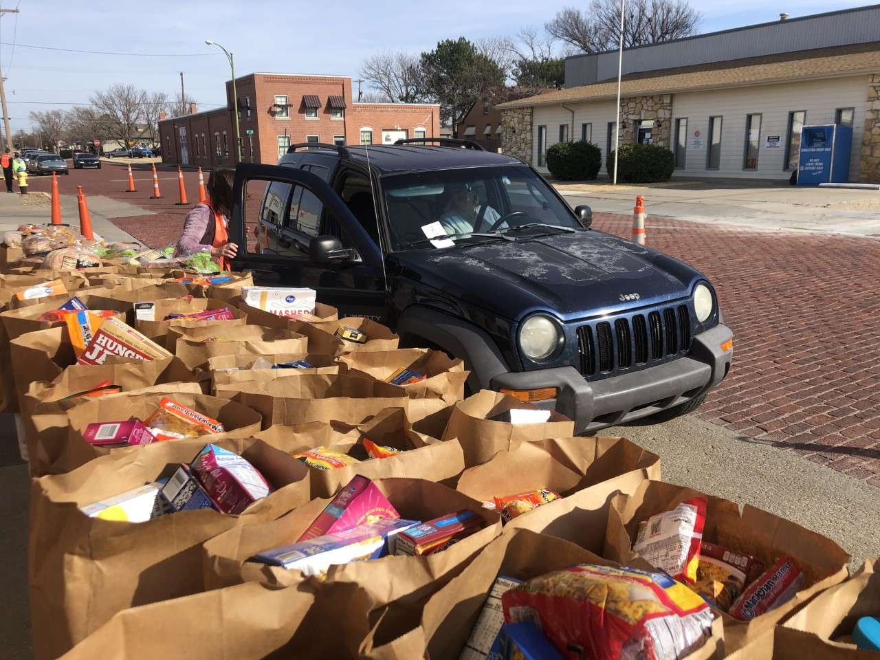 A volunteer loads a vehicle with a free bag of groceries. 