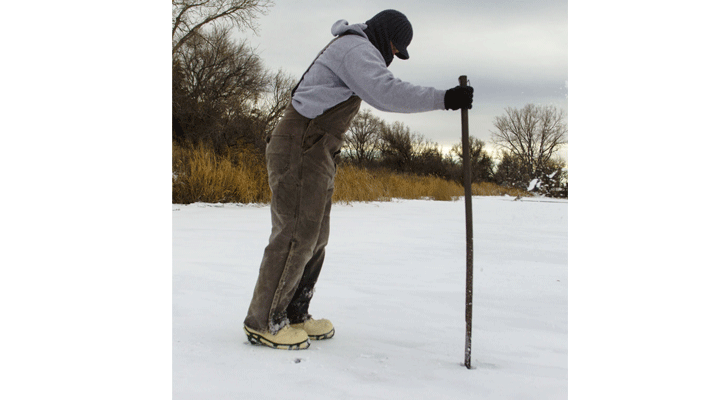 Jared Lorensen, fisheries biologist with the Nebraska Game and Parks Commission, uses a spud bar to check ice conditions before heading out with his ice-fishing equipment. (Nebraskaland Magazine/NGPC)