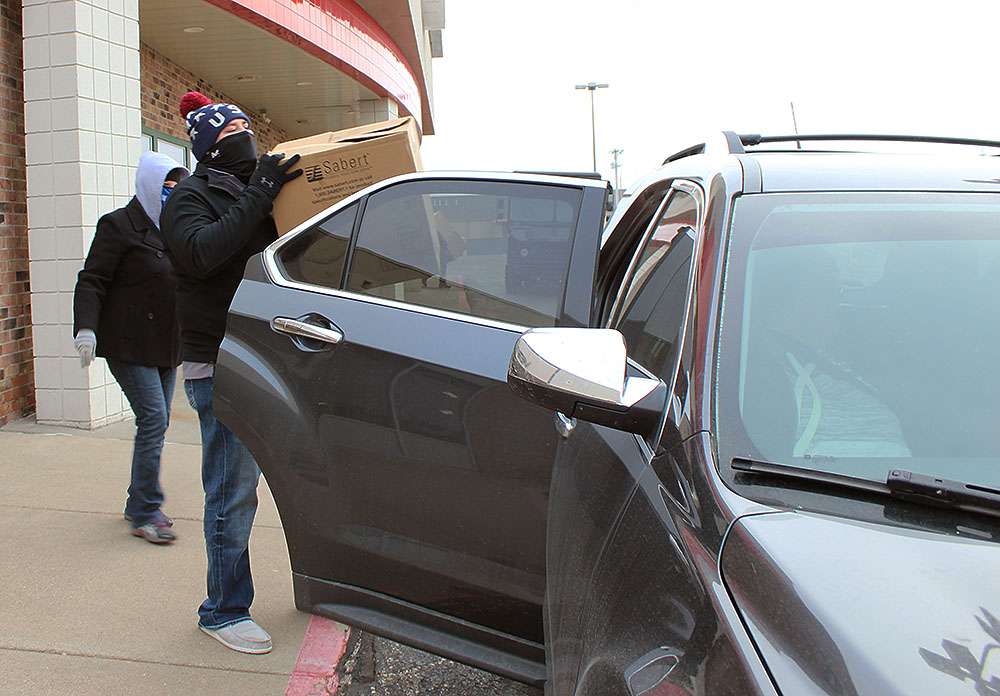A volunteer loads Christmas dinners in a vehicle during the Community Christmas Dinner meal pick up Wednesday at Thirsty's.