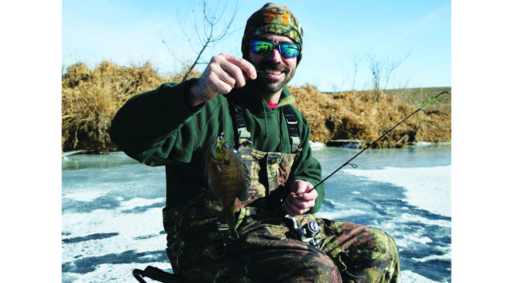 An ice angler dressed in layers on a sunny day shows off his bluegill. A parka or jacket could be added as a layer if the temperature drops or wind picks up. (Nebraskaland Magazine/NGPC)