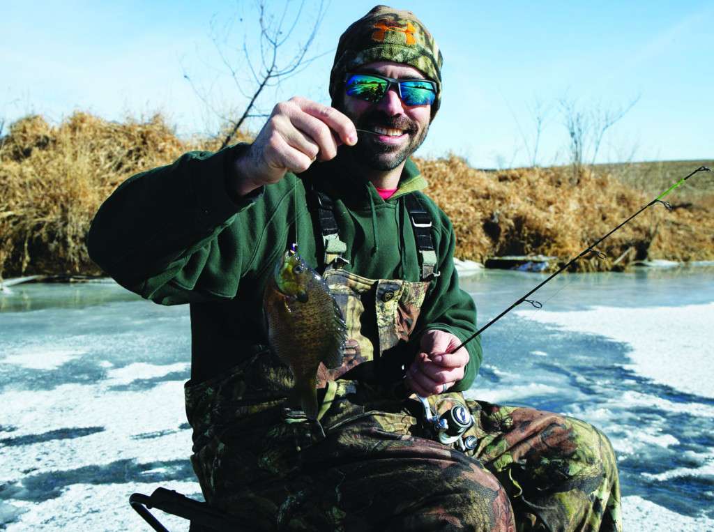 An ice angler dressed in layers on a sunny day shows off his bluegill. A parka or jacket could be added as a layer if the temperature drops or wind picks up. (Nebraskaland Magazine/NGPC)