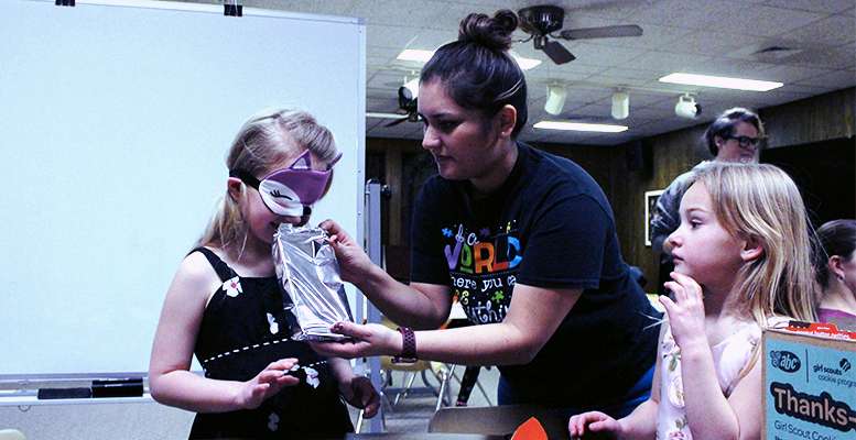 A Girl Scout sniffs a package of cookies to try to determine what kind of cookie they are during the Cookie Kick off Sunday in Hays.