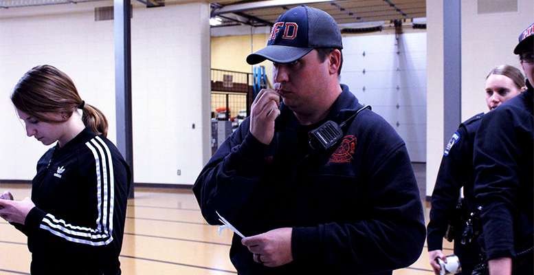 Lucas Everett, Hays firefighter, swabs his cheek for the national bone marrow registry. Everett said he had considered becoming a part of the registry for some time. Hays firefighter Allison Friesen (not pictured) also submitted a sample for the registry at the Tiger's home basketball game Feb. 6.