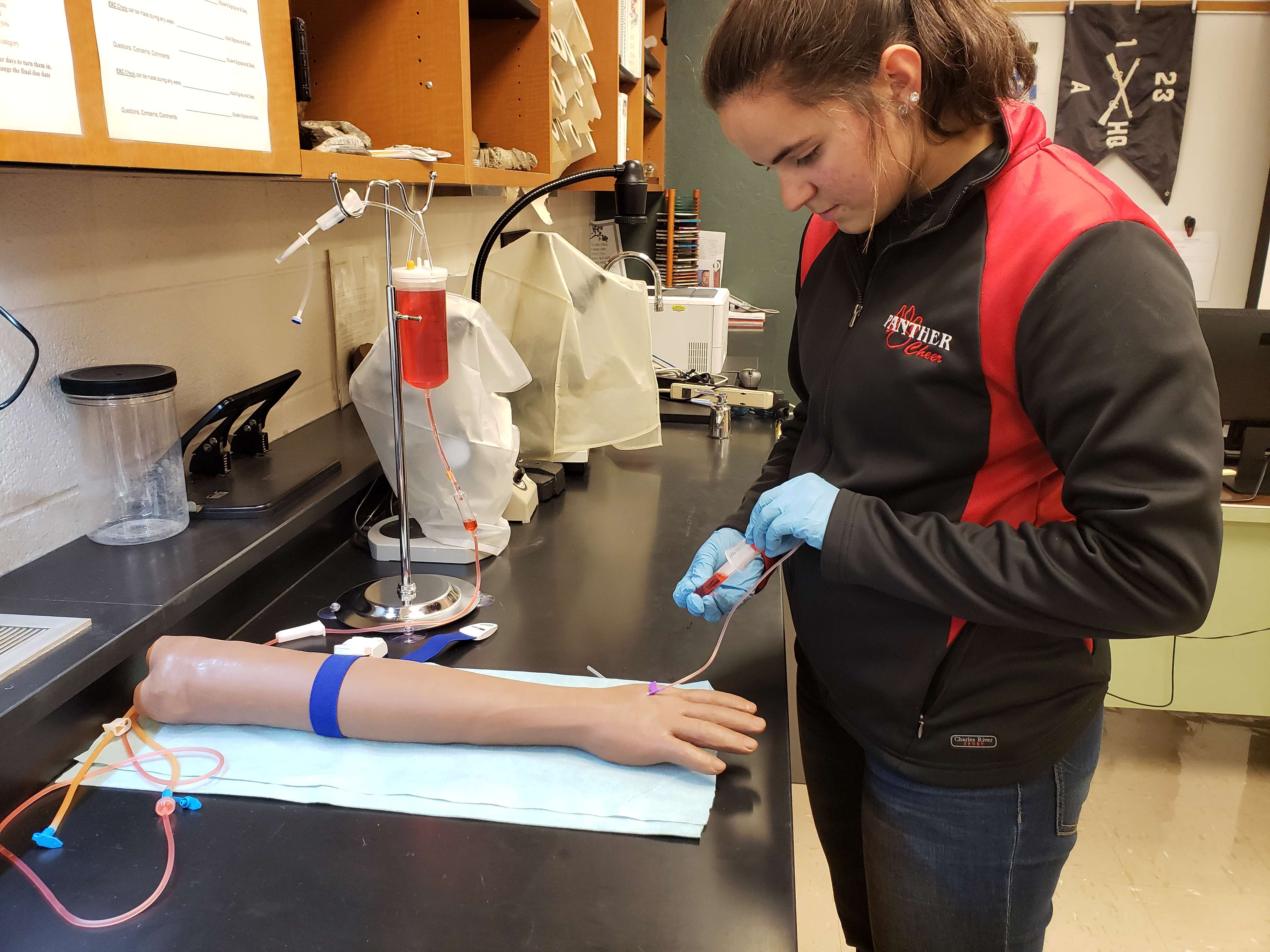 Exploring the basics of phlebotomy (blood draws, Emma Mayhill practices venipuncture skills on a simulation arm. Thanks to a recent grant from Midwest Energy, GBHS was able to increase their capabilities and inventory, now offering a Medical Arts Independent Study Lab at no charge to students.