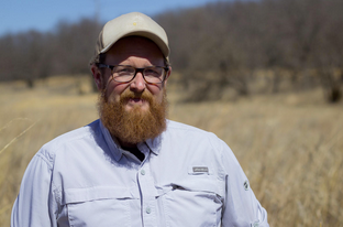 Field biologist Matt Garrett stands in front of one of the restored prairies at Shawnee Mission Park. Credit Brian Grimmett / Kansas News Service