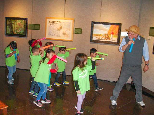 Gallery Director Dave Barnes leads a group of children on an imaginary wildlife expedition as part of the Our Connected World: Biodiversity in the Art of Carel Pieter Brest Van Kempen Exhibit.