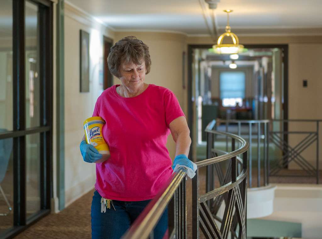 Custodian Rose Fankhauser wipes down the balcony railing in the main lobby at Crites Hall. (Photo by Daniel Binkard/Chadron State College)