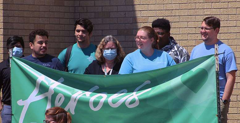 KVC Hospital employees stand in back of a "Heroes Work Here" sign at the KVC Hays location on Tuesday. The hospital administration organized two car caravans to honor the employees who have been working throughout the COVID-19 pandemic. Photos by Cristina Janney