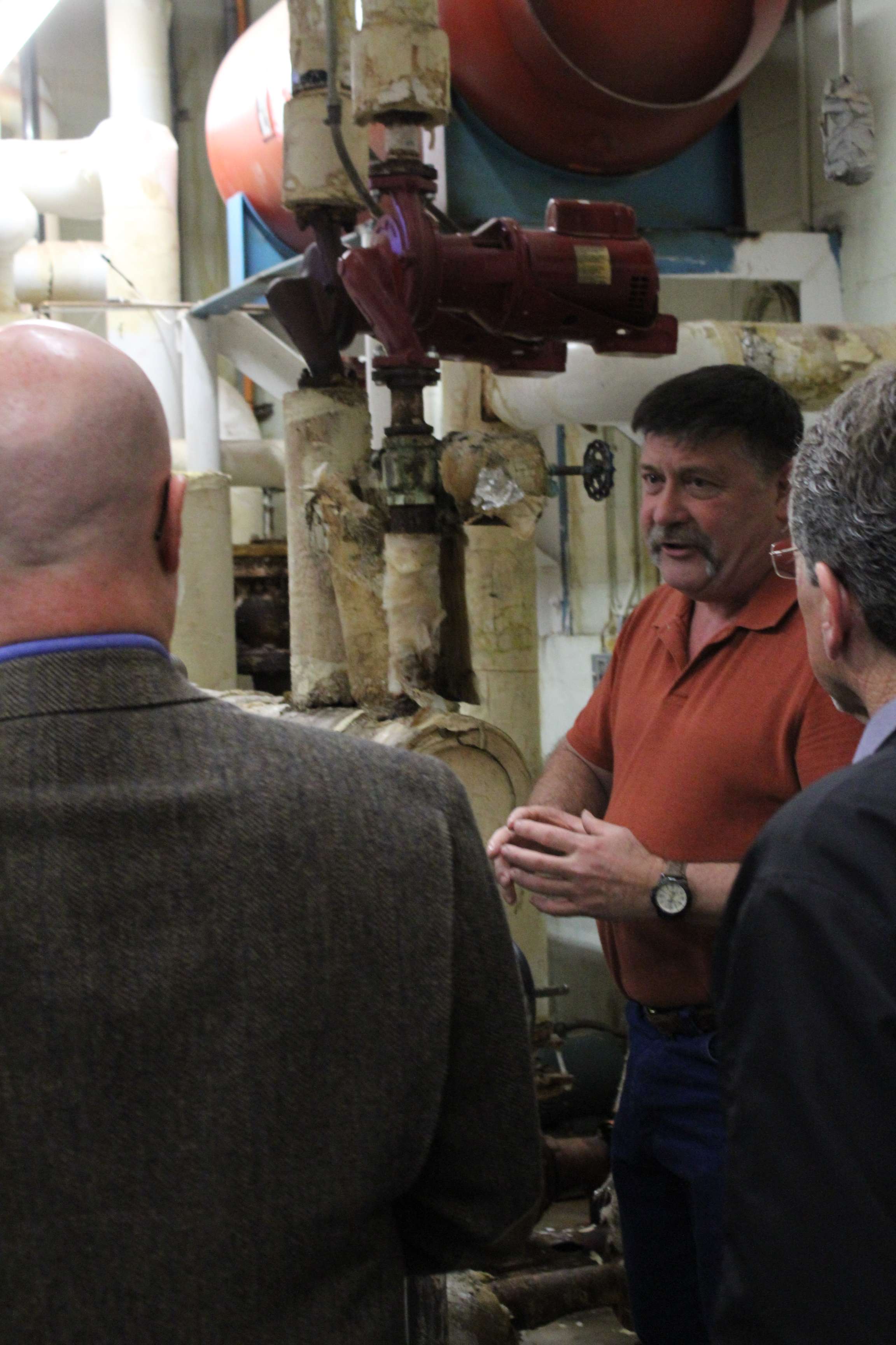 Building and grounds director Rusty Lindsay speaks with school board members inside the Roosevelt boiler room during a tour of the school earlier this school year. Photo by Cristina Janney