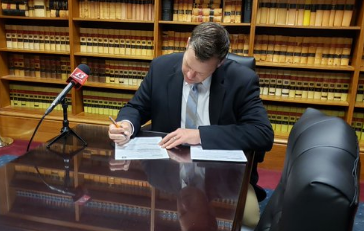 Kris Kobach signing the paperwork necessary to run for the open U.S. Senate seat. -Photo Kobach for Senate campaign