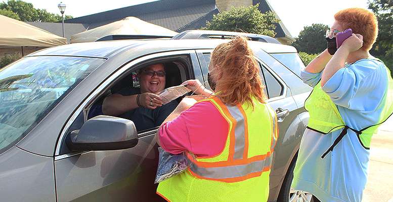 A woman smiles as she receives a free mask for her child during the Backpacks for Kids distribution Thursday at the First Presbyterian Church in Hays.