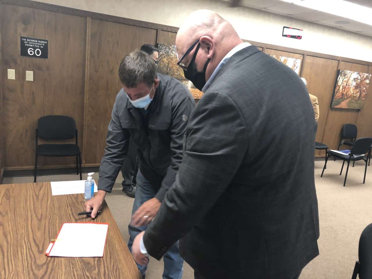 Hays developer Mark Ottley (left) signs official paperwork from Kim Rupp, Hays financial director, agreeing to build a stormwater retention mitigation project that will benefit the city downstream from his property north of I-70.