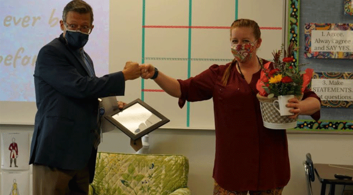 Dr. Ron Hanson, Superintendent of Schools, presents the Bulldog Staff Member of the Month award to Brittany McDaniel, who teaches speech and drama at North Platte High School.