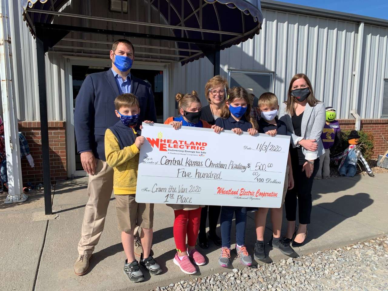 Regan Reif (right), Member Services and Key Accounts Manager, and Matt Hiss of Hiss Sherman Wealth Management Group (left), present a $500 check to students and staff of Central Kansas Christian Academy in Great Bend.