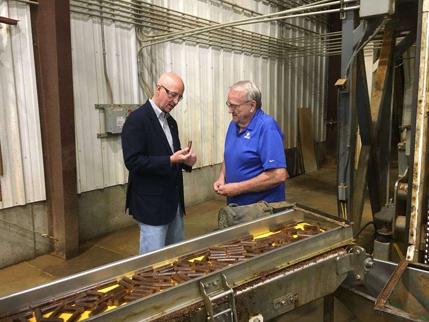 Gov. Ricketts (left) examines one of the pellets made by Nebraska Distillers Products at the company’s plant in Ord  on a tour with co-owner and production manager Gaylord Boilesen.