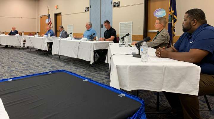 <b>Salina City Commission candidates, the media panel, video personnel, and Salina Area Chamber of Commerce and Salina League of Women Voters officials were spaced throughout the chamber annex meeting room during the forum Tuesday night. The candidates, from left, Douglas Alt, Chad Farber, Michael Hoppock, Jerry Ivey II,&nbsp;Greg Lenkiewicz, Bill Longbine, and Matthew Smith.</b> Salina Post photo