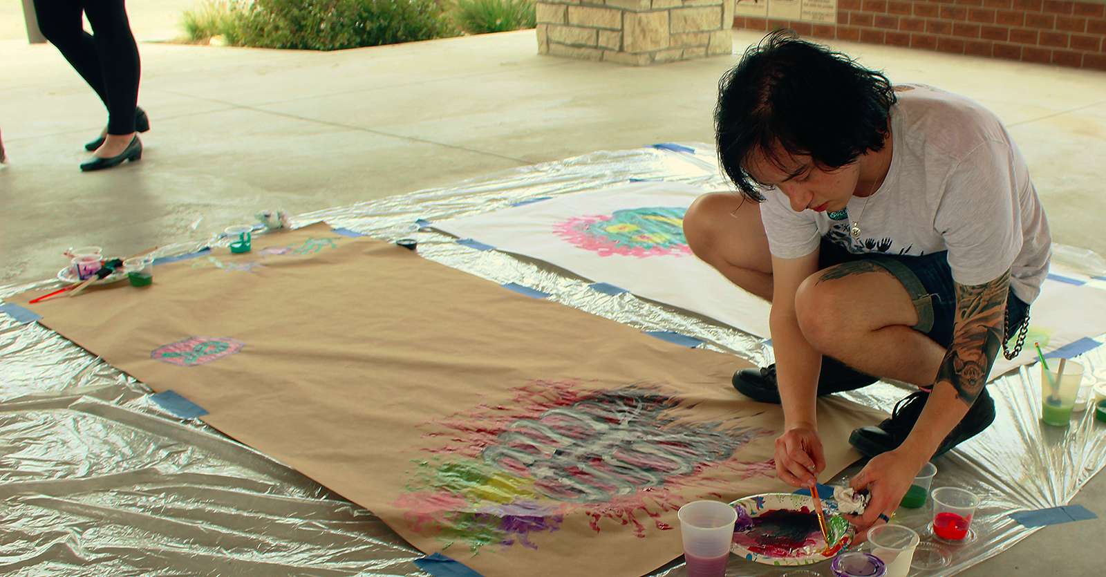 FHSU student Kiernan McCarty paints at the Paint the Town Purple event Oct. 9 to show his support of survivors of domestic violence.<br>