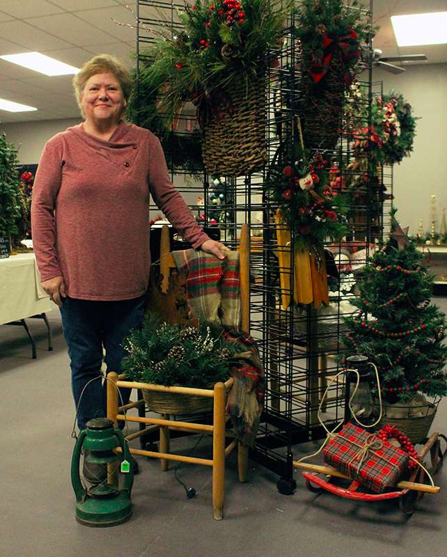 Volunteer Donna McKenzie with a couple of the arrangements she made for the Arc Festival of Trees.<br>