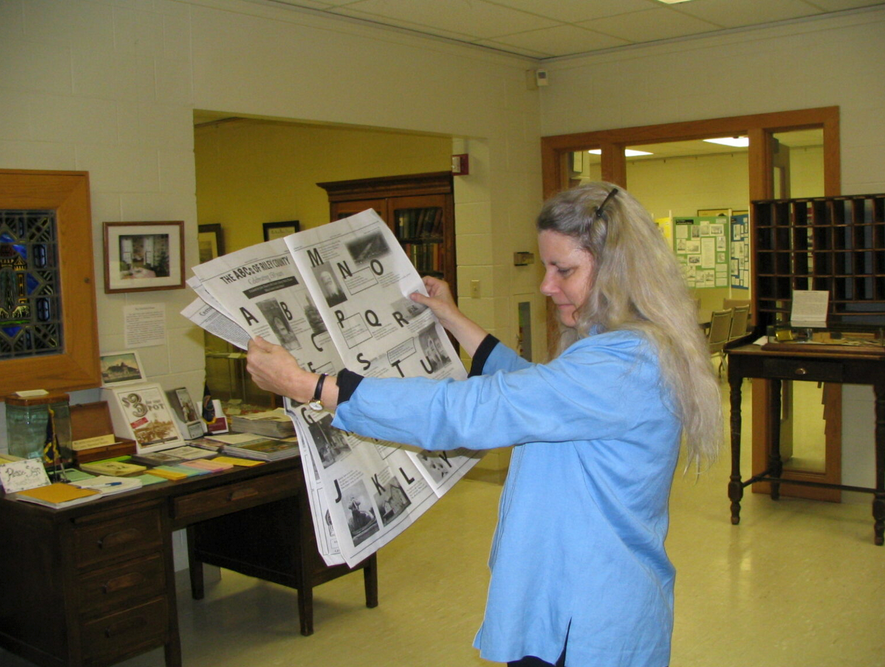  Cheryl Collins reads “The ABCs of Riley County,” written by Riley County Grade School sixth-graders. The spread was part of “Riley County Legacy,” a special section produced by grade school, junior high, high school and college students for the 2005 sesquicentennial of Manhattan and the county. (Gloria Freeland, courtesy Kansas Reflector)