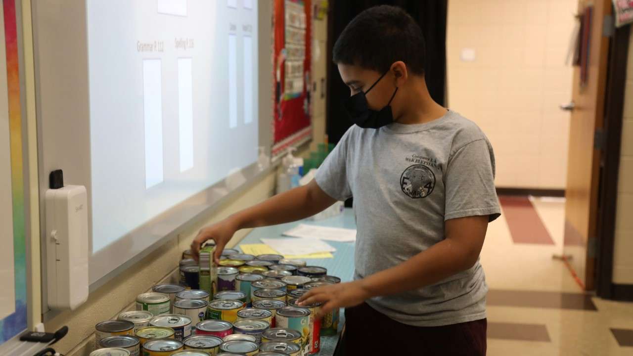 Fort Riley Middle School student RJ Shed organizing the cans collected from his food drive.
