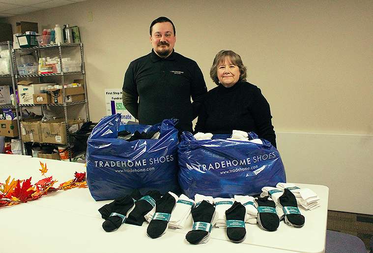Christopher Huntley, Tradehomes Shoe manager, presents Linda Mills, executive director of First Call for Help with donated socks.<br>