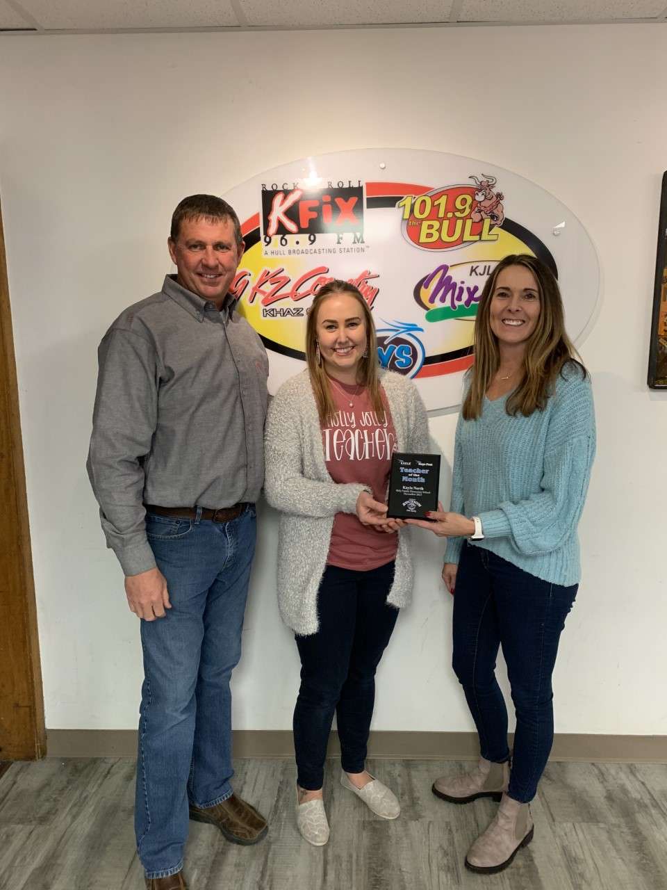 Mark Ottley, right, and Lynette Ottley, left, owners of Nations Auction Elite Realty, honor the November Hays Post Teacher of the Month Kayla North, center, kindergarten teacher at Holy Family Elementary School.<br>
