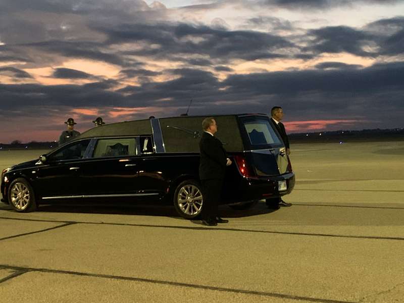 <b>Kansas Highway Patrol troopers and funeral home representatives stand by as the casket is taken off the plane.</b>