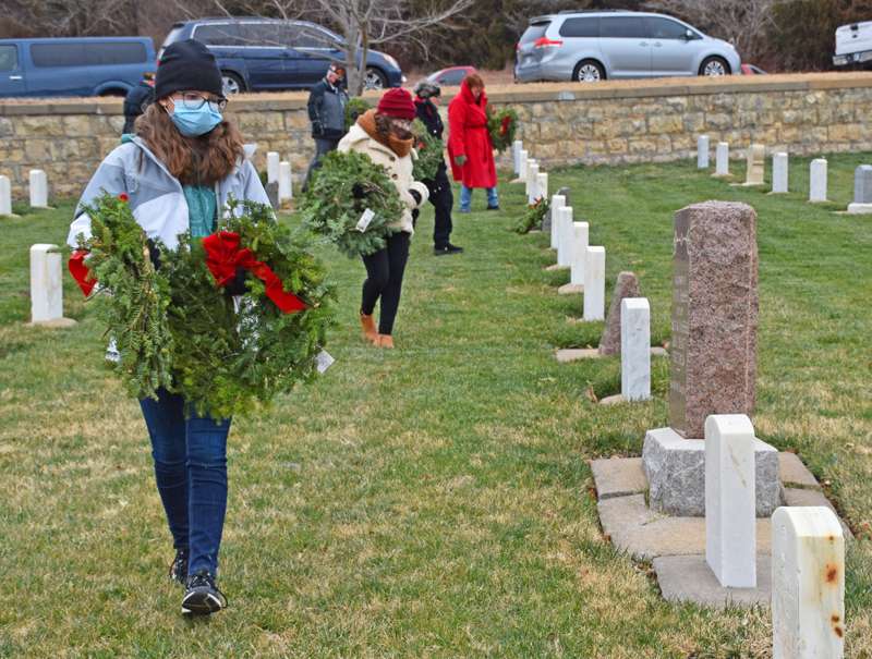 <b>Volunteers place wreaths on service members' graves.</b>