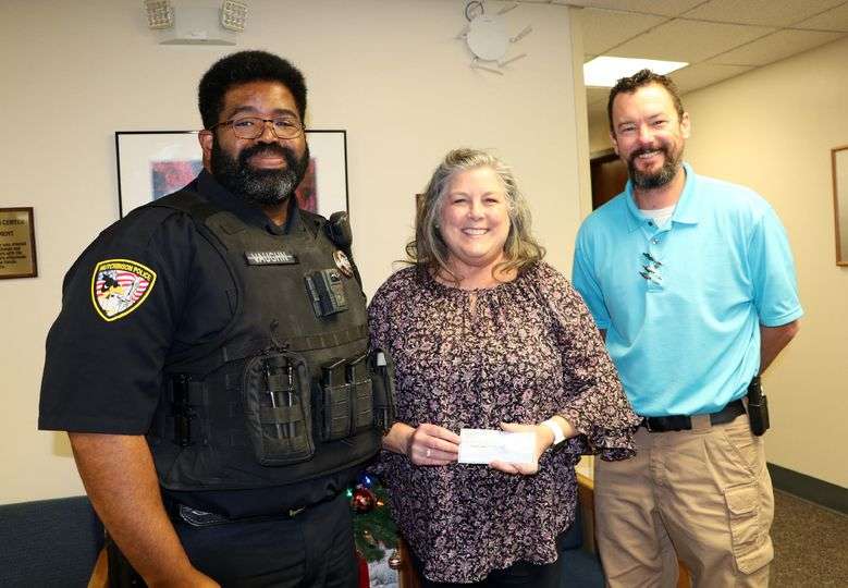 Hutchinson police officer Wesley Vaughn (FOP Lodge #7) and Reno County Sheriff Detective Sergeant Andrew Soule (FOP Lodge #18) present Reno County Youth Services Director Shelly Bredemeier with a check for the youth in the shelter.