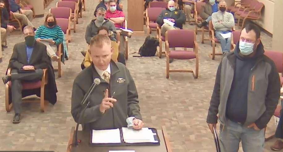 James Graham (front left) who objects to the Big Creek Estates 2nd Addition plat development, listens to Adam Pray, developer, (at podium) and James Meis (right) with Driggs Design Group engineers.