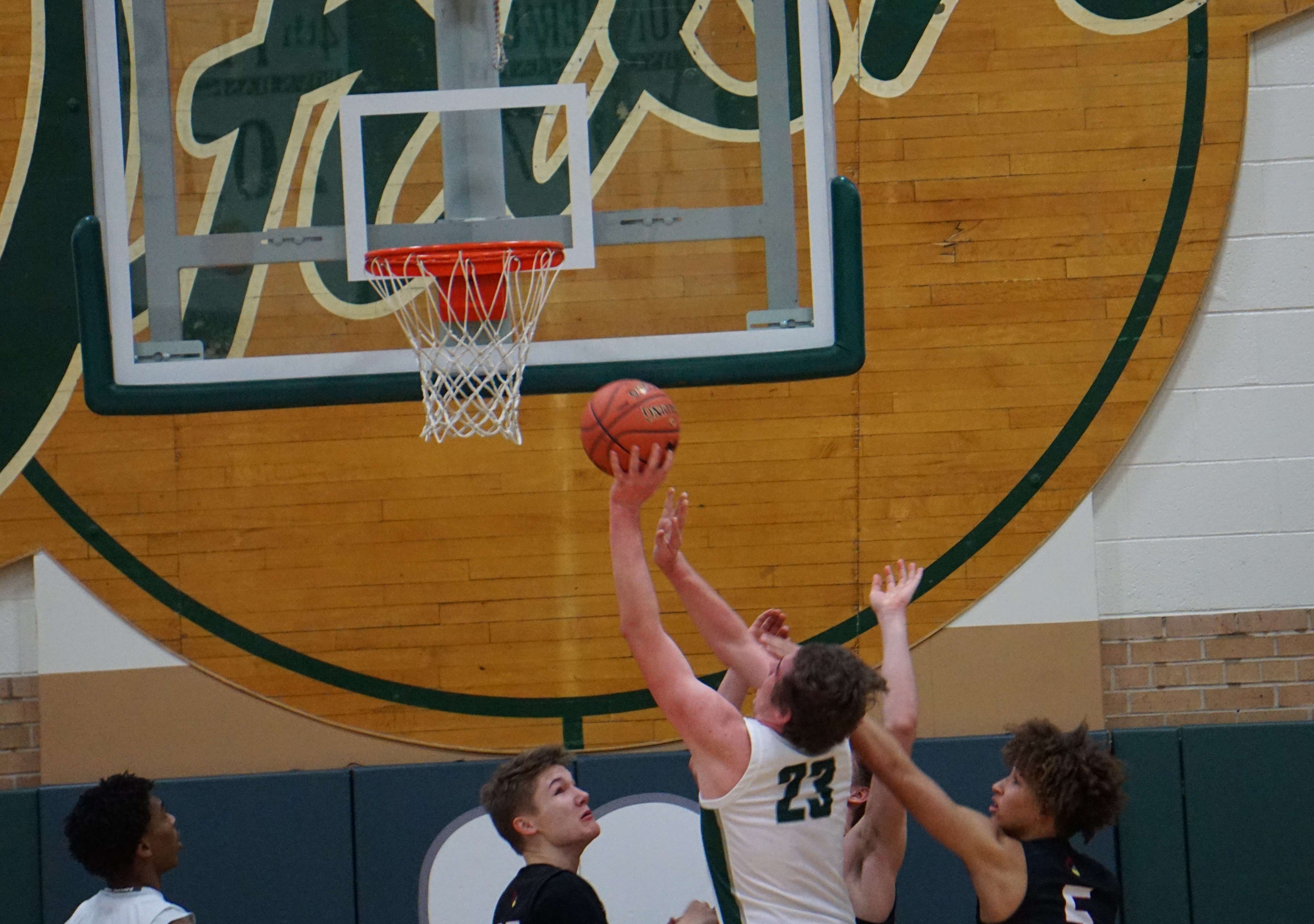 Zach Langley (23) puts up a contested shot against Benton's Damian Justus (5) in the Irish's 63-33 win Tuesday. Photo by Tommy Rezac.