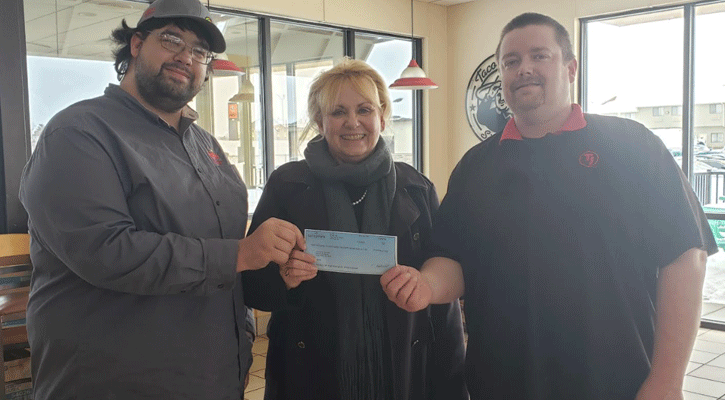 Taco John's Fourth Street location manager Wyat Halstead (left) and General Manager JD Szwanek present North Platte Area Habitat for Humanity Executive Director Dalene Skates with a check from the Nachos Navidad promotion.