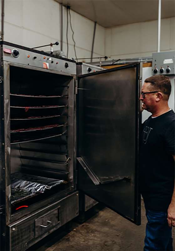 Chris&nbsp;Schumacher, new Pat's Beef Jerky owner, taking a batch of beef jerky out of the oven at their plant in Liebenthal. Courtesy photo