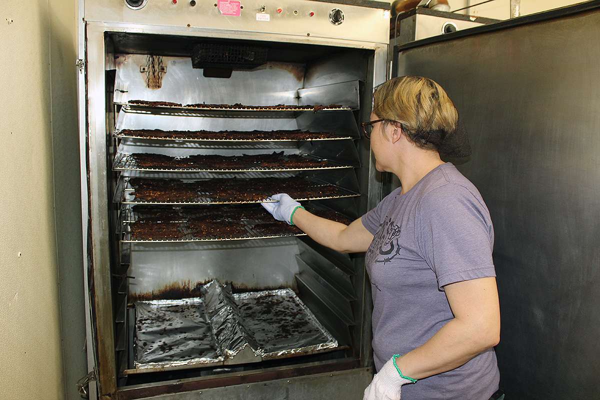 Pat's Beef Jerky employee Heather LaPorte removes beef jerky from an oven. Cristina Janney/Hays Post