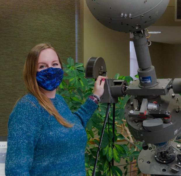 Dr. Tawny Tibbits stands next to the retired optical mechanical projection ball on display in the Mari Sandoz High Plains Heritage Center, March 26, 2021. (Photo by Abigail Swanson/Chadron State College)<br>