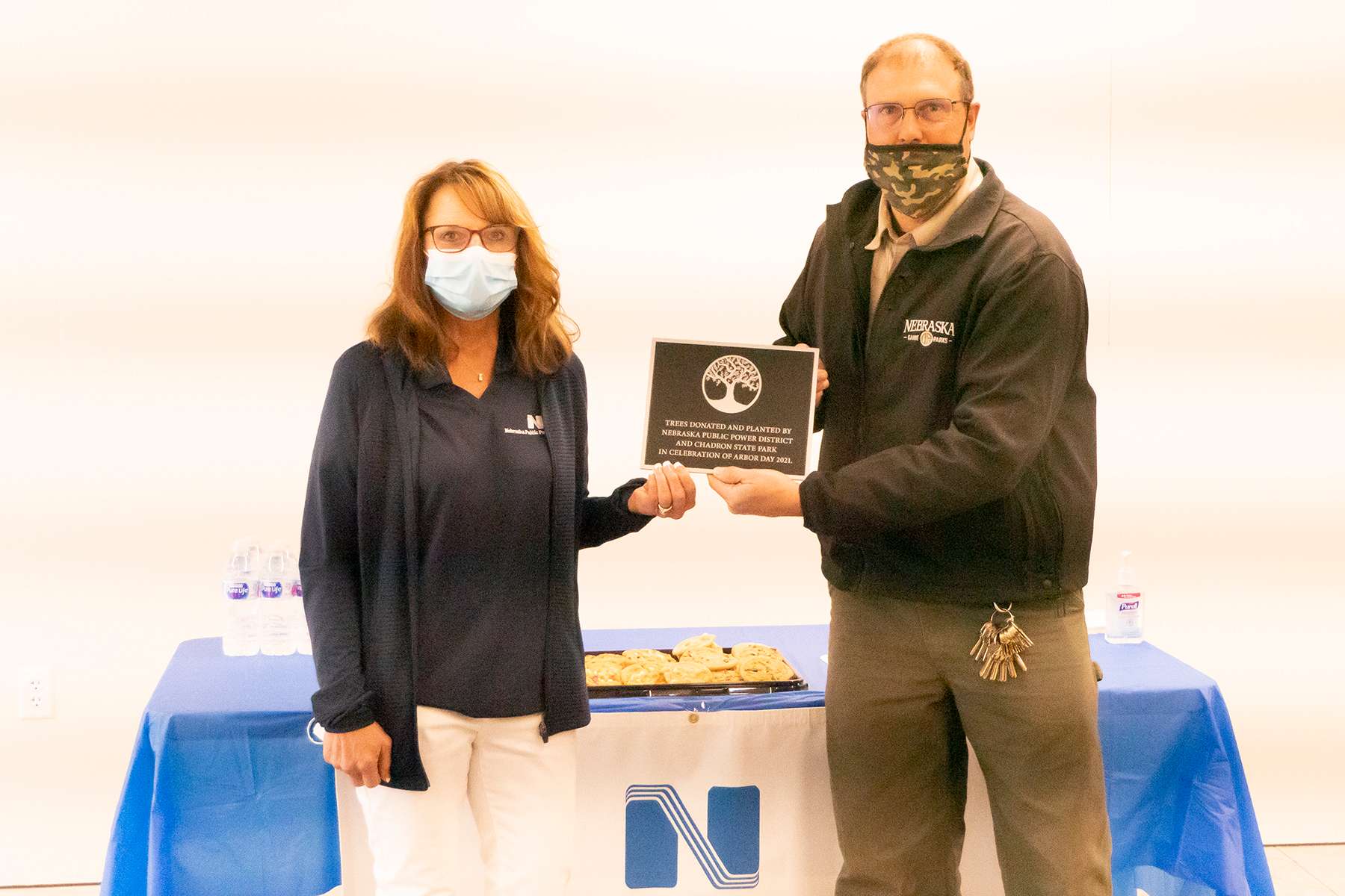 Nebraska Pubic Power District Account Manager Melody Baily and Chadron State Park Superintendent Gregg Galbraith hold a plaque commemorating the nine new trees donated and planted in Chadron State Park.&nbsp;