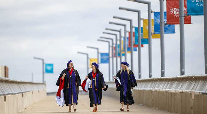 Nebraska Law graduates (from left) Claudia Brock, Sarah O’Neill and Rachel Lowe walk across the pedestrian bridge toward Pinnacle Bank Arena before commencement on May 7. Photo: Craig Chandler-University Communication