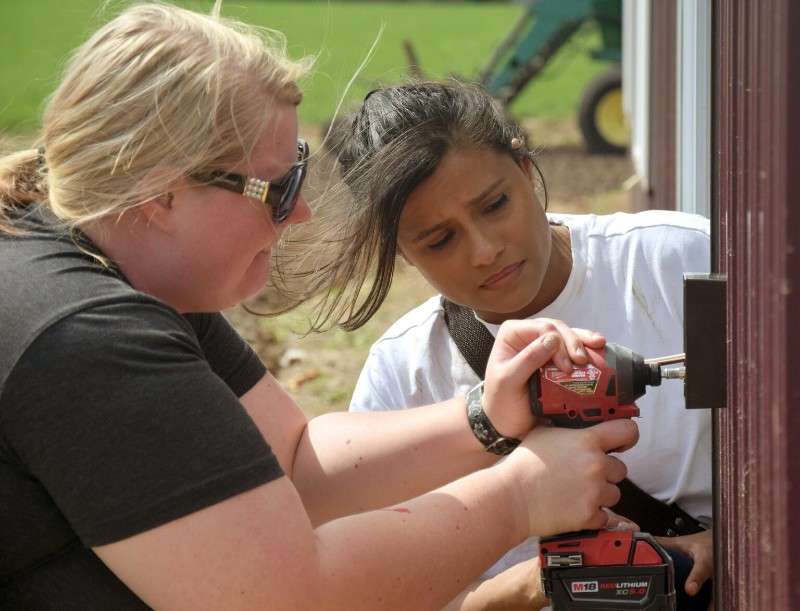 <b>Megan Vesterberg, left, and Beronica Cruz work on wiring an outdoor outlet on a new home in southwestern Saline County on April 27 as part of a class project. Both graduated from Salina Area Technical College’s Electrical Technology program in May. </b>(Salina Area Technical College)