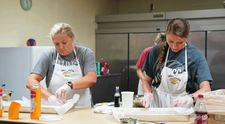 Volunteers Clancy Hammond and Kylie Wroot prepare cinnamon rolls for distribution during the Sweet Saloon Monday at McDaid Elementary in North Platte. (Photo: Heather Johnson)