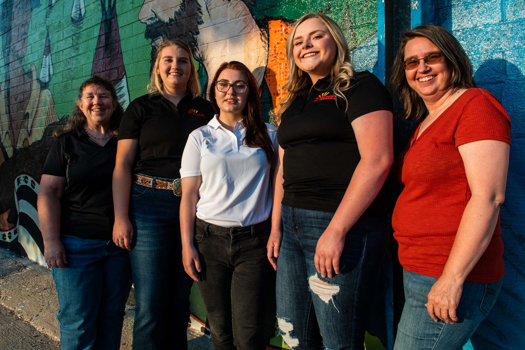 The three Rural Fellows and several local partners pause in front of one of the downtown Chadron murals. From left to right are Jenny Nixon, RPN Educator; Rural Fellows Chantelle Schulz, Hanna Jemison, and Jacy Hafer; and Kerri Rempp, Tourism Director for the Discover Northwest Nebraska Tourism office in Chadron. Not pictured Terri Haynes, ESU 13 - AWARE Project Manager for the Chadron Public Schools.