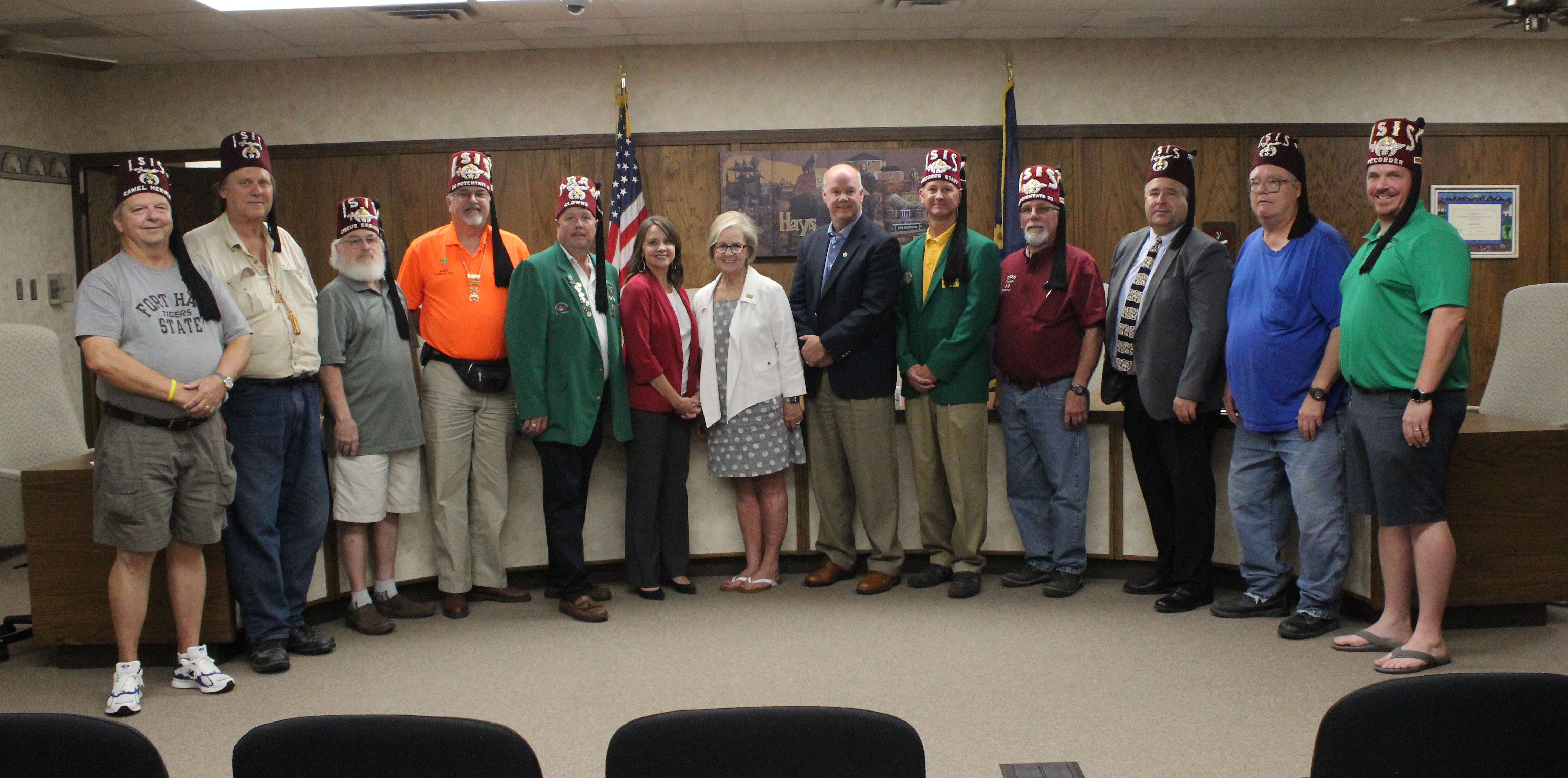 Center Melissa Dixon, Hays Convention and Visitors Bureau director; Sandy Jacobs, Hays mayor; and Curtis Hammeke, Fort Hays State University athletics director; with state and local Shriners announced Hays will host the 2023 Shrine Bowl.