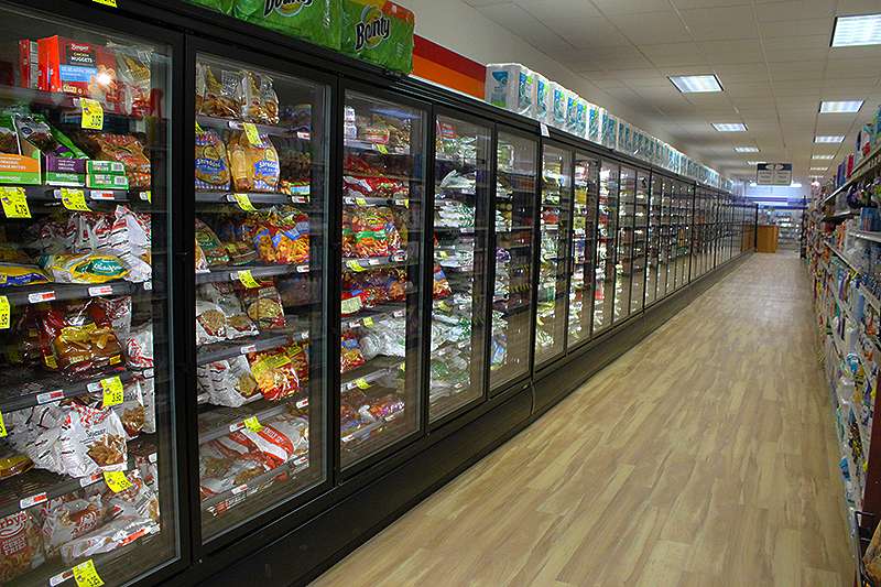 John Girard, owner of Girard's grocery, replaced old refrigeration units in an attempt to cut electricity costs and stay competitive with chain stores.