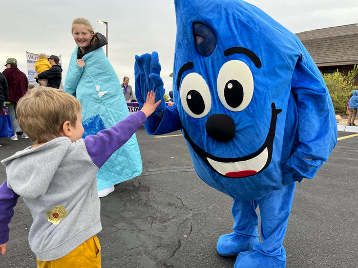 The Hays water conservation program's mascot, WaterSmart Wally, gives out high fives at a recent street fair. Wally is just one sign of how far the town's water-saving culture has come since the 1990s. David Condos / Kansas News Service