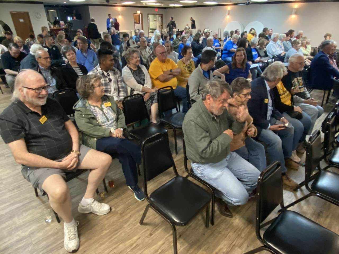 Audience members await the start of&nbsp; the Wasinger-Hammond forum at the Rose Garden Banquet Hall in Hays. Many in the Wasinger camp wore bright blue T-shirts, while gold and black T-shirts were prevalent among the Hammond supporters.